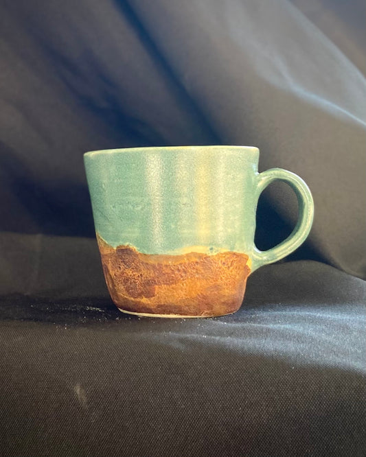 Handthrown ceramic mug, antique blue glazed with amber-iron oxide wash. Two-tone texture surface, matte and satin. Hand-textured rugged rocky mountain landscape. Hand-pulled handle..