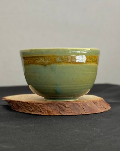 Handcrafted ceramic bowl with smooth celadon glaze and cacao shino detail