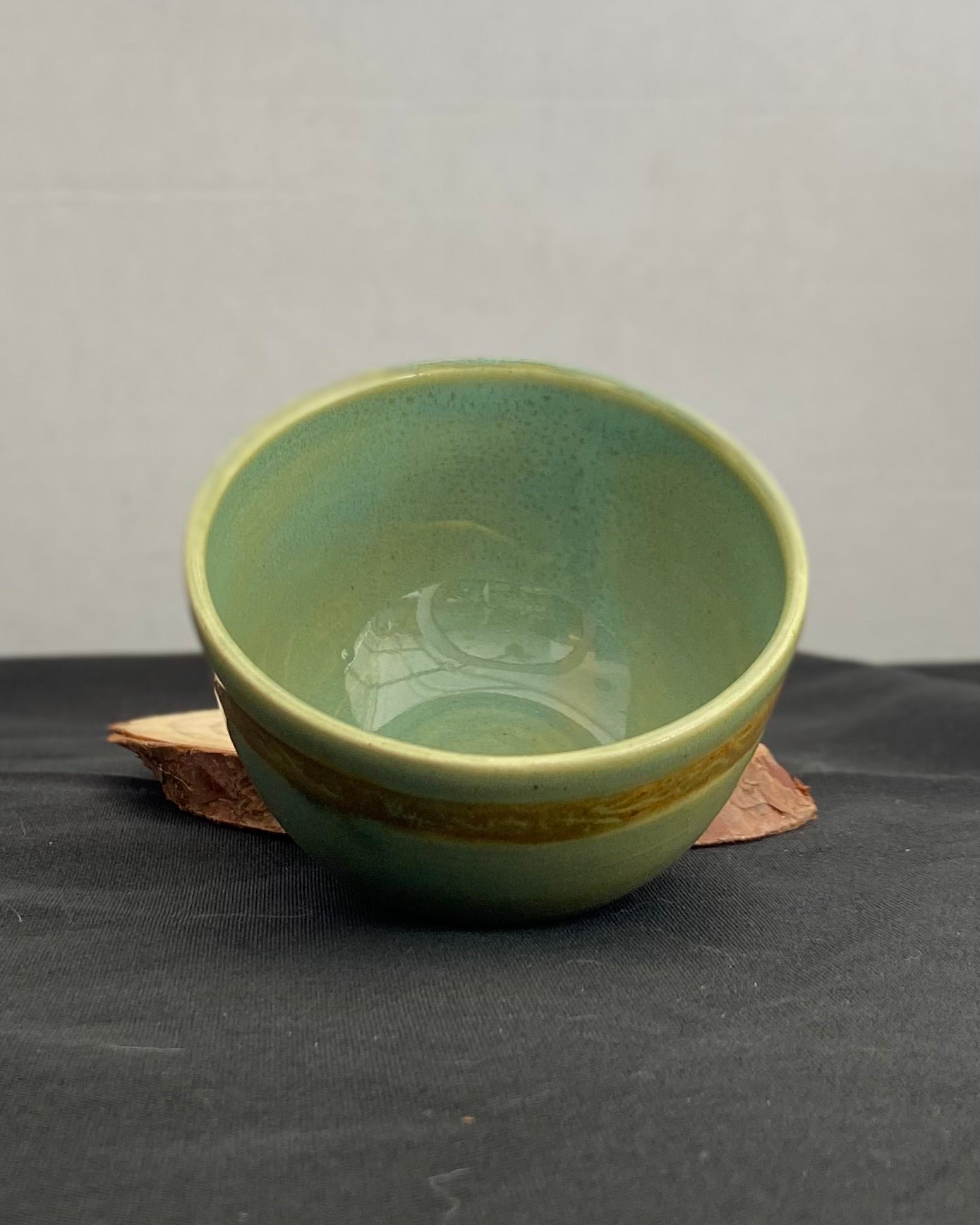 Handcrafted ceramic bowl with smooth celadon glaze and cacao shino detail