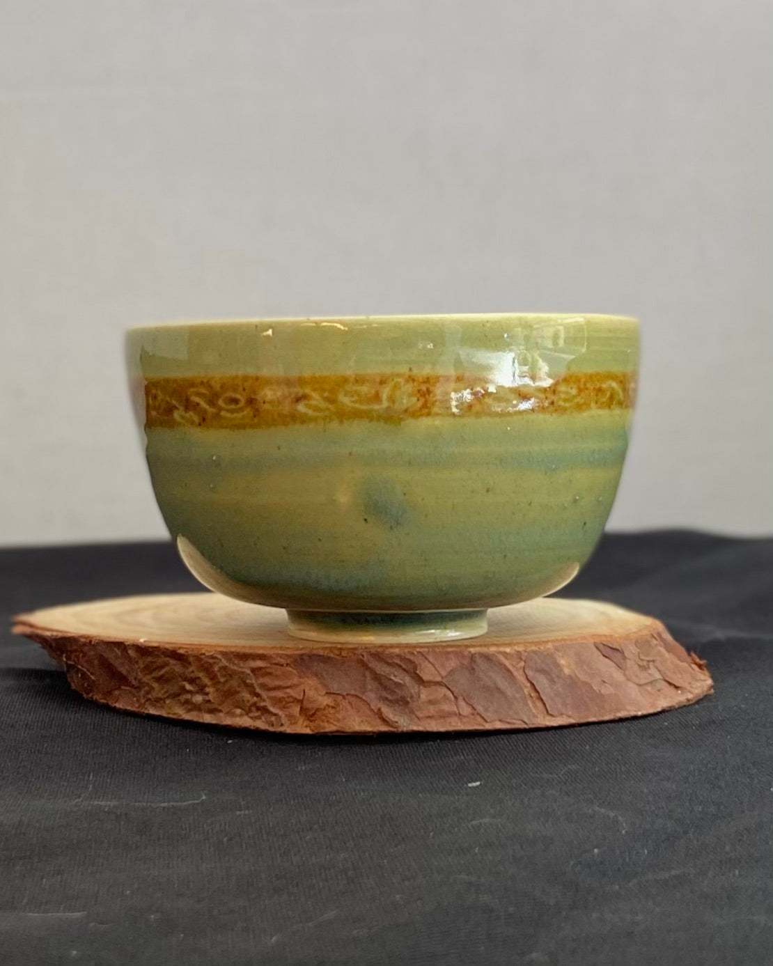 Handcrafted ceramic bowl with smooth celadon glaze and cacao shino detail