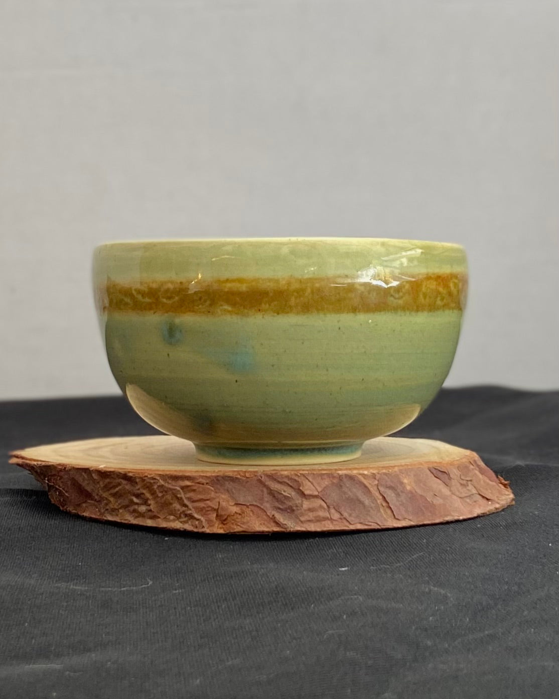 Handcrafted ceramic bowl with smooth celadon glaze and cacao shino detail