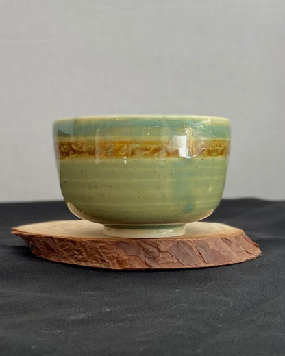 Handcrafted ceramic bowl with smooth celadon glaze and cacao shino detail