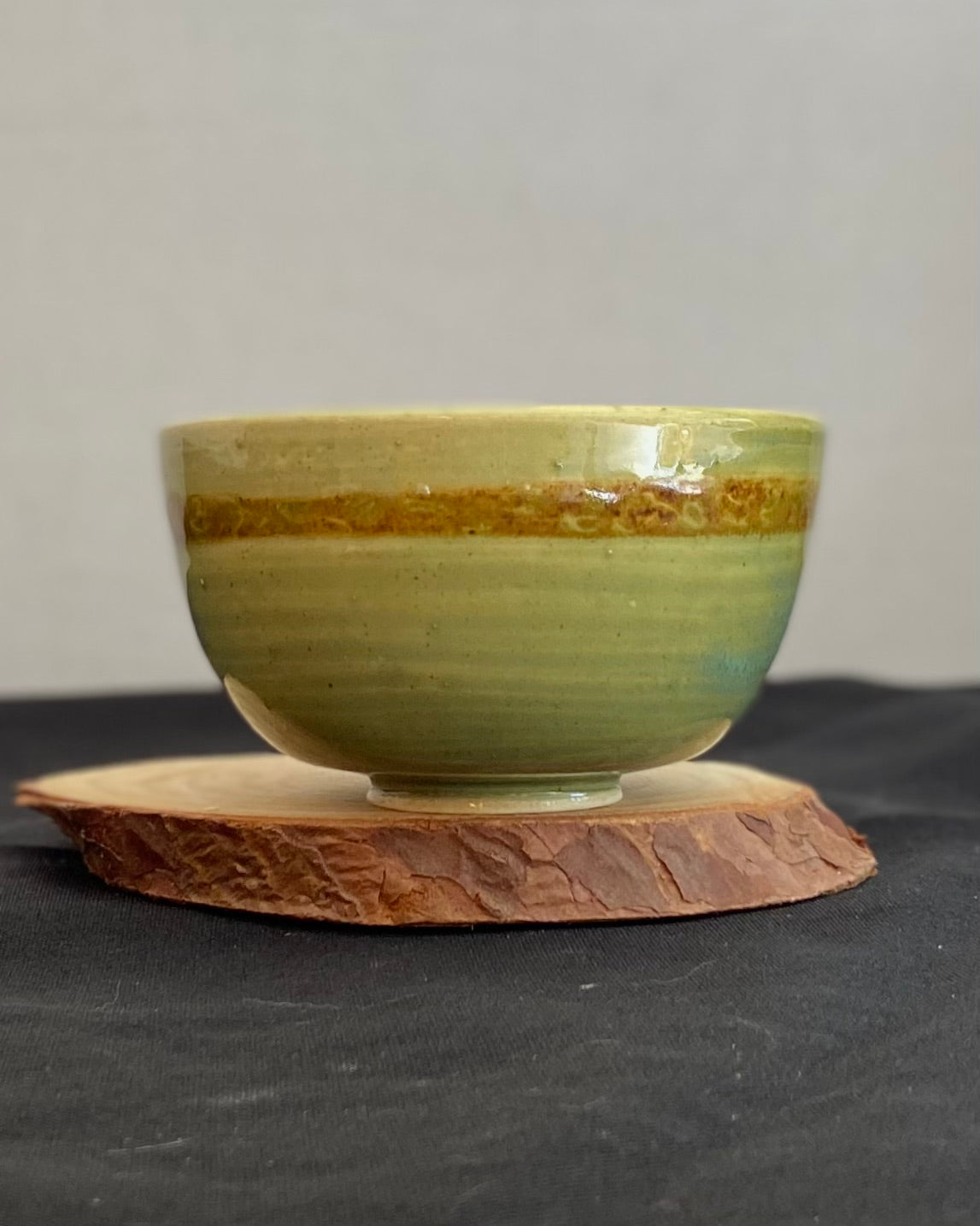 Handcrafted ceramic bowl with smooth celadon glaze and cacao shino detail