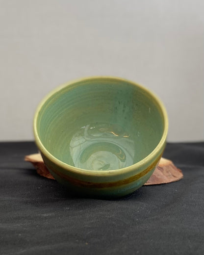 Handcrafted ceramic bowl with smooth celadon glaze and cacao shino detail