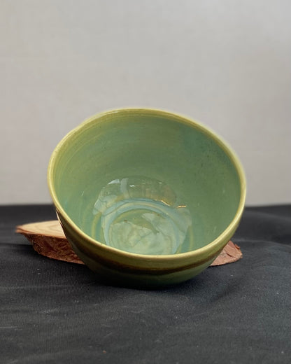 Handcrafted ceramic bowl with smooth celadon glaze and cacao shino detail