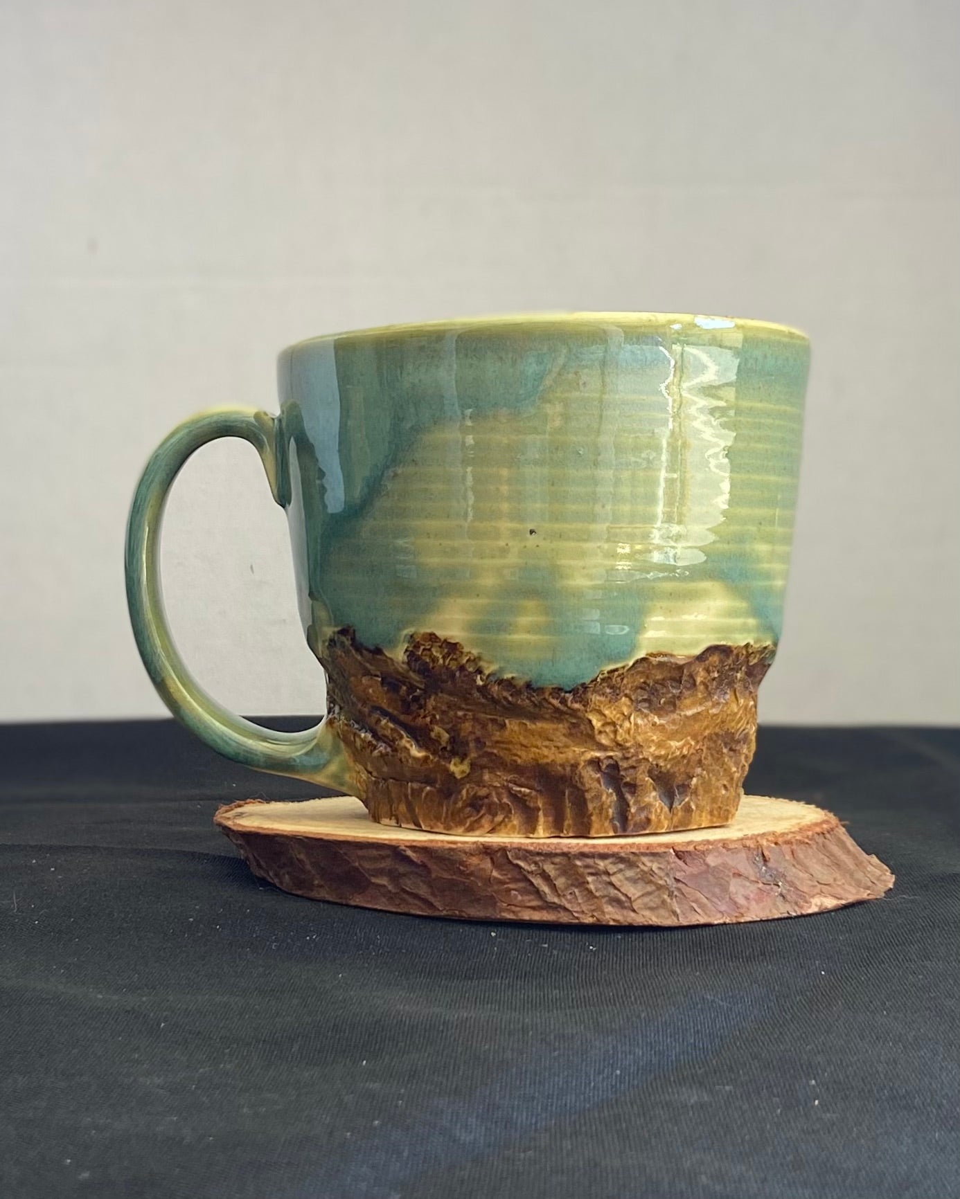 Handcrafted Mountain Mug with glossy celadon sky glaze and rocky textured mountainscape, accented with iron oxide and matte amber quartz glaze. Unique ceramic mug inspired by outdoor rock climbing, perfect for coffee or tea. Artisan quality, wabi sabi design, and playful glaze details