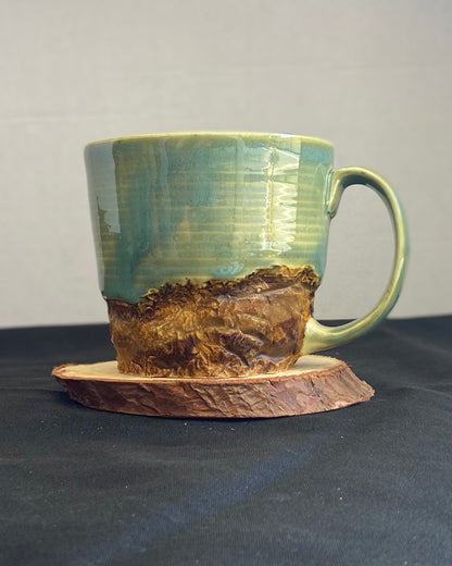 Handcrafted Mountain Mug with glossy celadon sky glaze and rocky textured mountainscape, accented with iron oxide and matte amber quartz glaze. Unique ceramic mug inspired by outdoor rock climbing, perfect for coffee or tea. Artisan quality, wabi sabi design, and playful glaze details