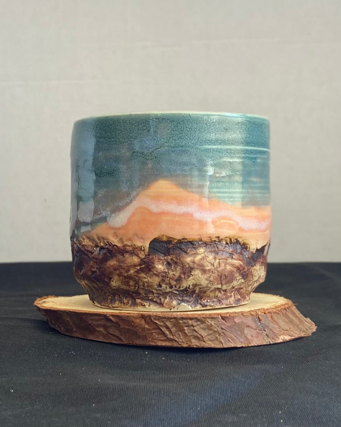 Handcrafted tumbler with hand-etched Joshua tree, antique blue satin glaze, and sunburnt pink glaze creating a sunset over a hand-carved mountain landscape. Unique ceramic tumbler inspired by nature, perfect for beverages. Artisan quality, wabi sabi design, and nature-inspired aesthetic