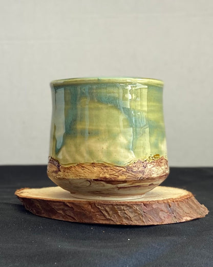 Handcrafted tumbler with hand-etched Joshua tree, celadon blue-green glaze over a hand-carved mountain landscape. Unique ceramic tumbler inspired by nature, perfect for beverages. Artisan quality, wabi sabi design, and nature-inspired aesthetic